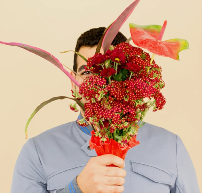 DaWanda team portrait: a person holding red flowers in front of their face.