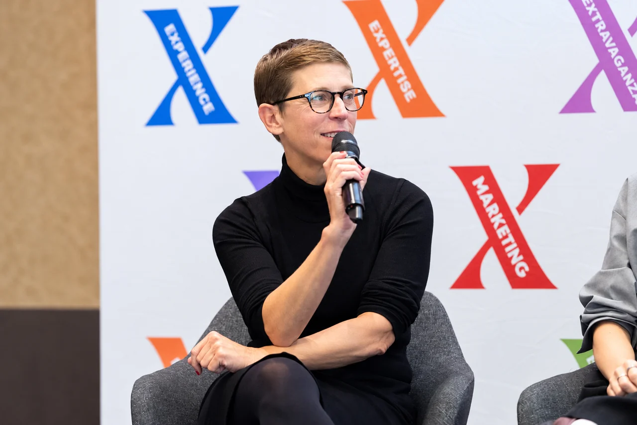 Kerstin Ludwig speaking into a handheld microphone during a MARKETING X panel. Photo: Elisabeth Kessler.